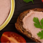Grobe Bratwurst auf einer Brotscheibe mit Petersilie und Tomate